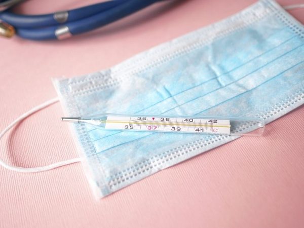 Thermometer and Face Mask sitting on a solid surface