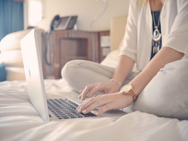 Woman sitting on the bed with her computer