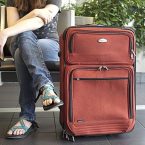 A lady sitting next to a large Suitcase
