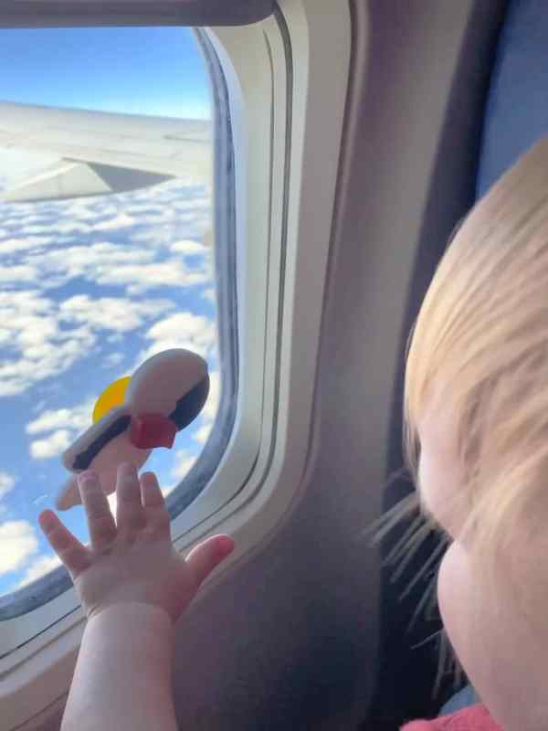 Baby playing with a toy in a plane window