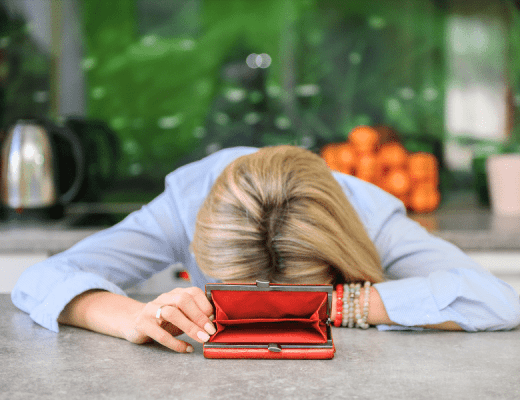 woman with her head on the desk and an open wallet with no money inside