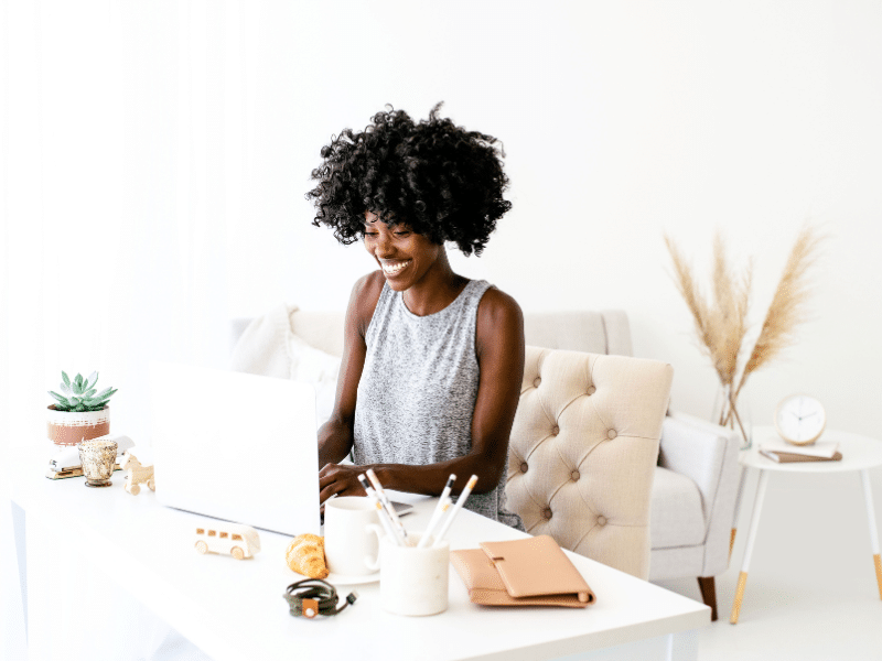 a woman sitting at a desk and smiling at the computer