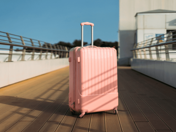 A pink suitcase sitting outside of an airport