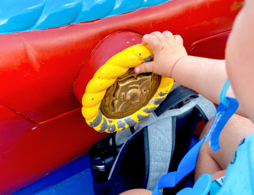 Baby on a Disney ride, holding onto the button in Magic Kingdom