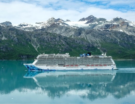 The Norwegian Bliss sailing on an Alaska Cruise with mountains in the background.