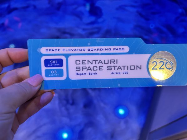 Holding up a boarding pass for the Space 220 elevator in Epcot, in Walt Disney World